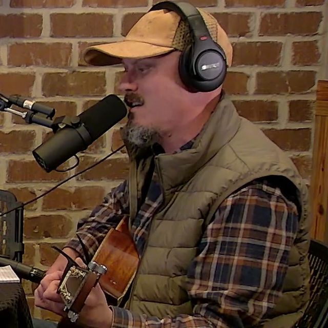 Joe Watkins playing guitar at the mic